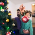 Criança e um homem decoram árvore de Natal