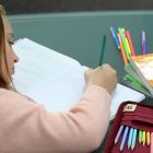 Menina está fazendo atividades escolares sozinha