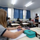 Professora está em sala de aula com estudantes respeitando o distanciamento e usando máscara