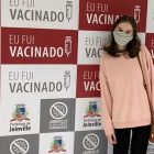 Jovem que tomou a vacina durante a madrugada faz foto em frente ao banner com a frase: eu fui vacinado