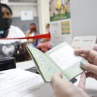 Atendente segura carteira de trabalho nas mãos enquanto atende uma trabalhadora