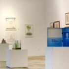 Quadros e objetos em exposição que trazem técnica de pontilhismo na galeria de arte