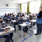 Alunos usando máscara em sala de aula de escola municipal