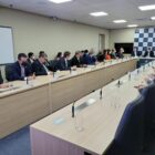 Políticos sentados reunidos em uma sala discutindo propostas