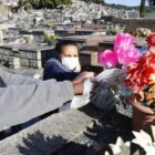 Mulher e homem colocam flores em cima de um túmulo