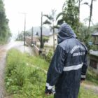 Técnicos da Defesa Civil usam capa de chuva e vistoriam área atingida