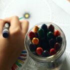 mão de criança desenhando em um papel com giz de cera