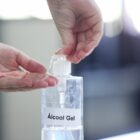 Foto mostra mão com frasco de álcool gel
