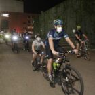 Pai e filho pedalam em uma bicicleta integrada e outros ciclistas aparecem atrás