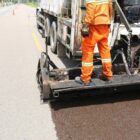 Trabalhador em caminhão que aplica asfalto em uma rua