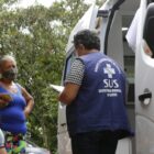 Agente comunitária de saúde ao lado de uma unidade móvel atende moradores