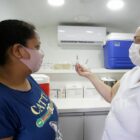 Enfermeira mostra seringa para paciente