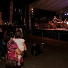 Mulher segura criança e assistem à apresentação no palco da praça Dario Salles