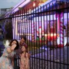 Mãe, pai e filha tiram foto em frente de casa com decoração natalina