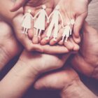 Mãos seguram uma figura de família recortada no papel