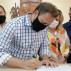Prefeito Adriano Silva assina documento enquanto é observado por outras autoridades