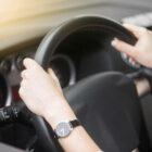 Imagem das mãos de uma motorista num volante de carro