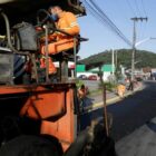 Homens trabalham colocando asfalto em uma rua.