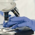 Profissional com luvas manipula um microscópio