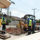 Homens e máquinas trabalham em obra em rua
