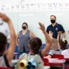 prefeito, vice-prefeita e secretário de educação em uma sala de aula com alunos da rede