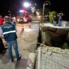 Bombeiros e técnicos da Defesa Civil observam local onde calçada cedeu