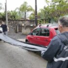 Agentes da Defesa Civil enrolam uma lona em rua