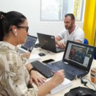 Três profissionais da educação sentados, estudando em frente a computadores