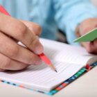 Homem segura um lápis e escreve em um caderno