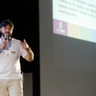 Secretário da saúde de Joinville no palco, com microfone na mão, faz palestra