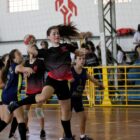 Meninas jogam handebol em uma quadra
