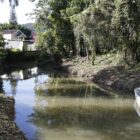 Foto de um rio com vegetação dos lados e um barquinho encostado