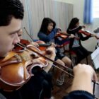 Alunos treinam violino em sala de aula