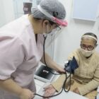 Enfermeira mede a pressão de paciente idosa