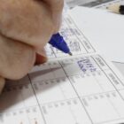 Mão de uma pessoa preenche uma carteira de vacinação