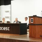 Secretária de Assistência Social fala em púlpito observada por autoridades em mesa