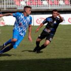 Dois jogadores disputam bola em partida em campo de futebol