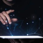 imagem de uma mão em direção a pontos de luz de um ipad