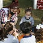 Professora de educação infantil em roda com crianças sentadas no chão escutando histórias
