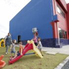 Imagem da frente de um CEI com crianças brincando no parque