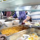 Pessoas se servem em buffet de comida no restaurante popular