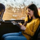 Usuária de transporte coletivo sentada em poltrona lendo uma revista