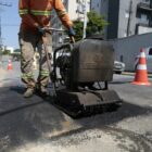 Homem trabalha com equipamento para pavimentar rua
