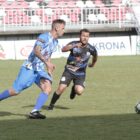 Dois jogadores disputam bola em campo de futebol