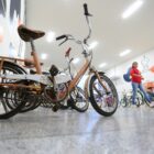 Bicicletas antigas expostas em hall, visitante observa