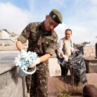 Soldado do exército e servidora recolhem material que acumula água em túmulo em cemitério