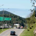 Foto de uma pista da BR 101 com um outdoor com a marca de Joinville em um terreno ao alto