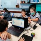 Alunos sentados olhando telas de computadores em uma sala de aula