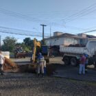 Caminhão, escavadeira e homens trabalham em rua
