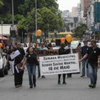 Pessoas em passeata em rua seguram cartazes sobre semana de conscientização de saúde mental